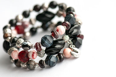 Voyage to Chinatown bracelet featuring a fortune cookie charm, spiral-carved Onyx beads, red and black swirl recycled glass, Cinnabarite beads, with Sardonyx and red garnet chips, complemented by silver-plated Chinese lantern spacers.