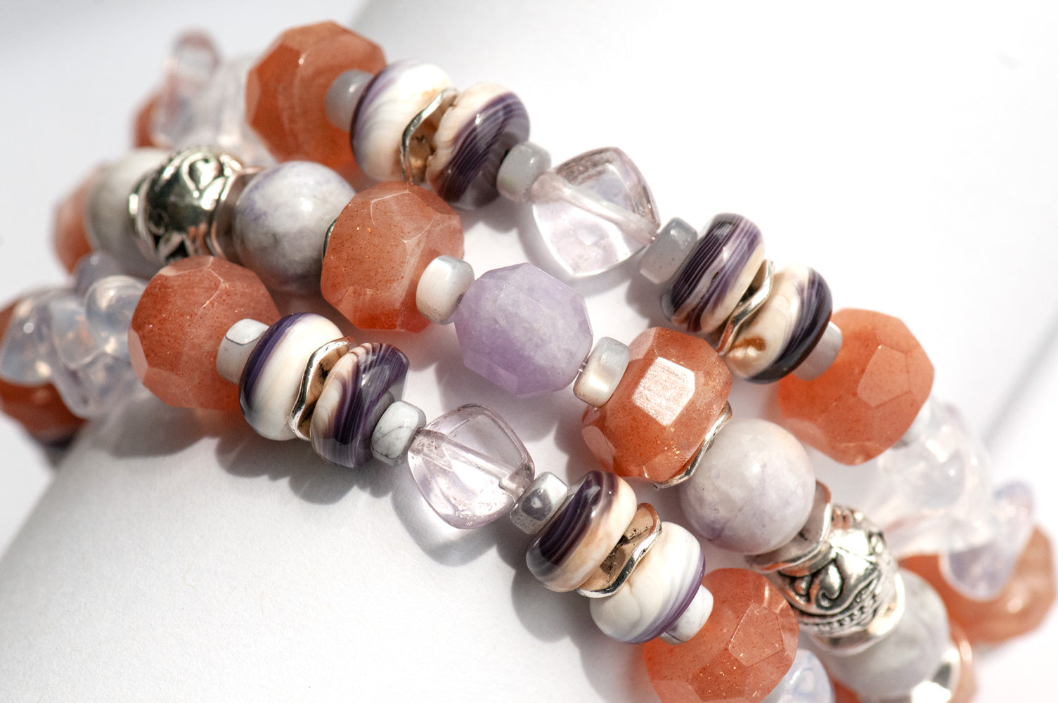 Sunstone, lavender amethyst, sugilite, and stunning wampum shell beads combine in this orange and purple handmade bracelet set. 