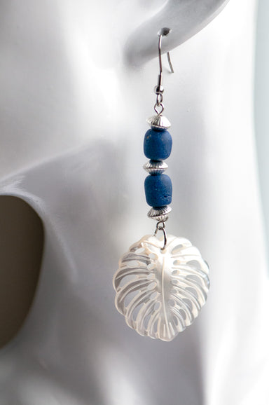 Daring dangle earrings featuring mother-of-pearl carved palm leaves accented with cobalt blue African recycled glass beads and silver-plated accents