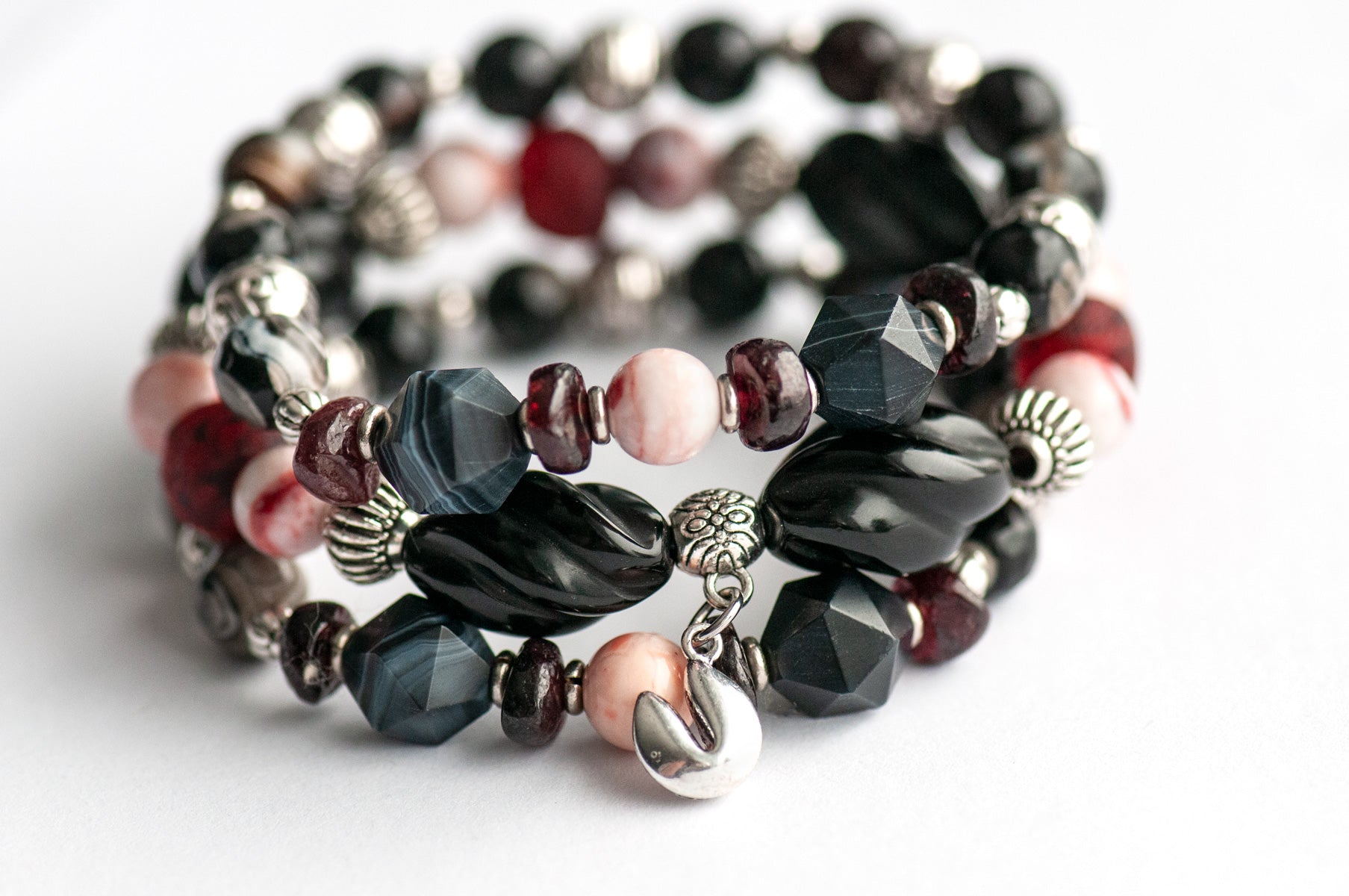 Voyage to Chinatown bracelet featuring a fortune cookie charm, spiral-carved Onyx beads, red and black swirl recycled glass, Cinnabarite beads, with Sardonyx and red garnet chips, complemented by silver-plated Chinese lantern spacers.