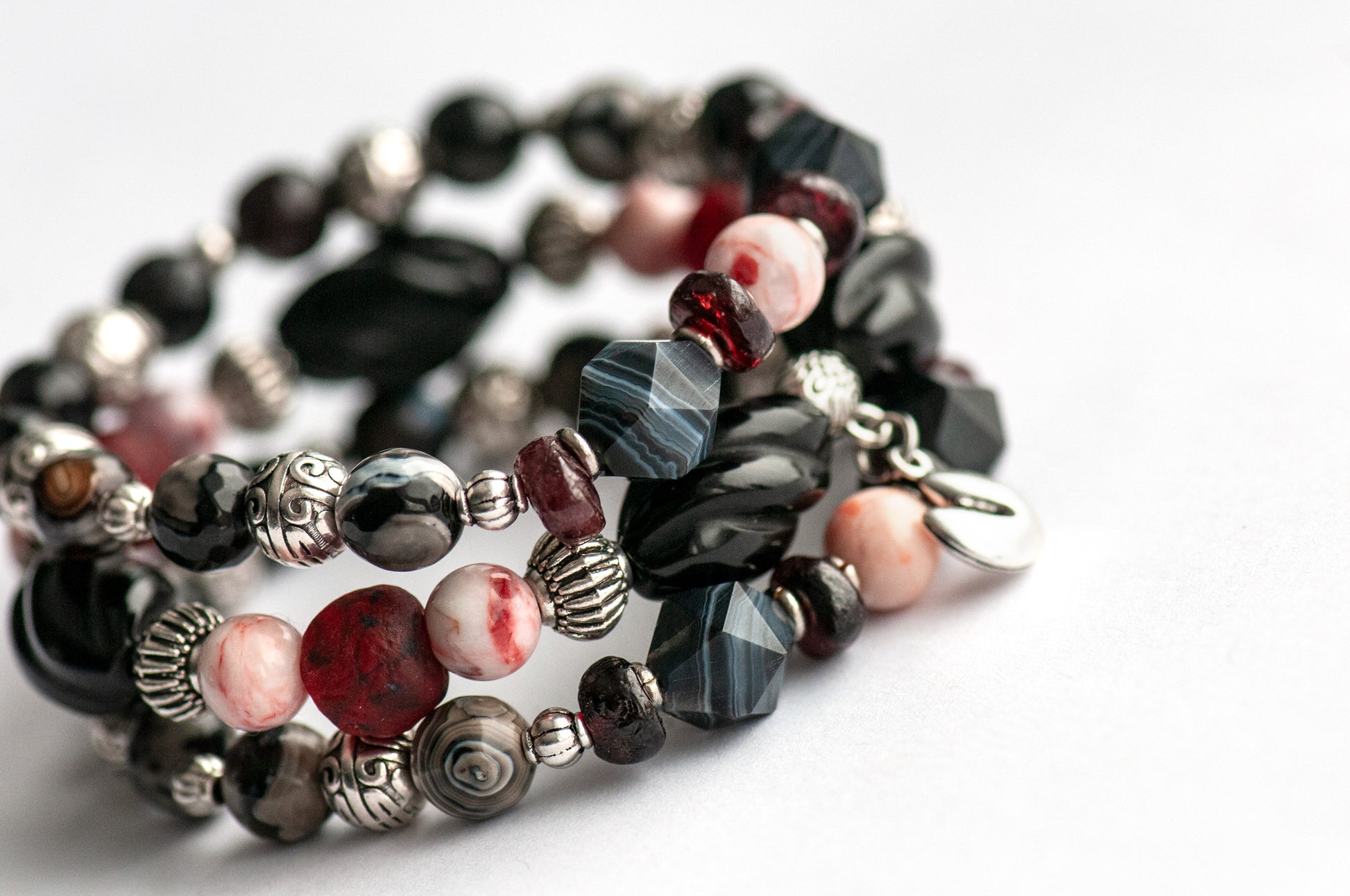 Voyage to Chinatown bracelet featuring a fortune cookie charm, spiral-carved Onyx beads, red and black swirl recycled glass, Cinnabarite beads, with Sardonyx and red garnet chips, complemented by silver-plated Chinese lantern spacers.