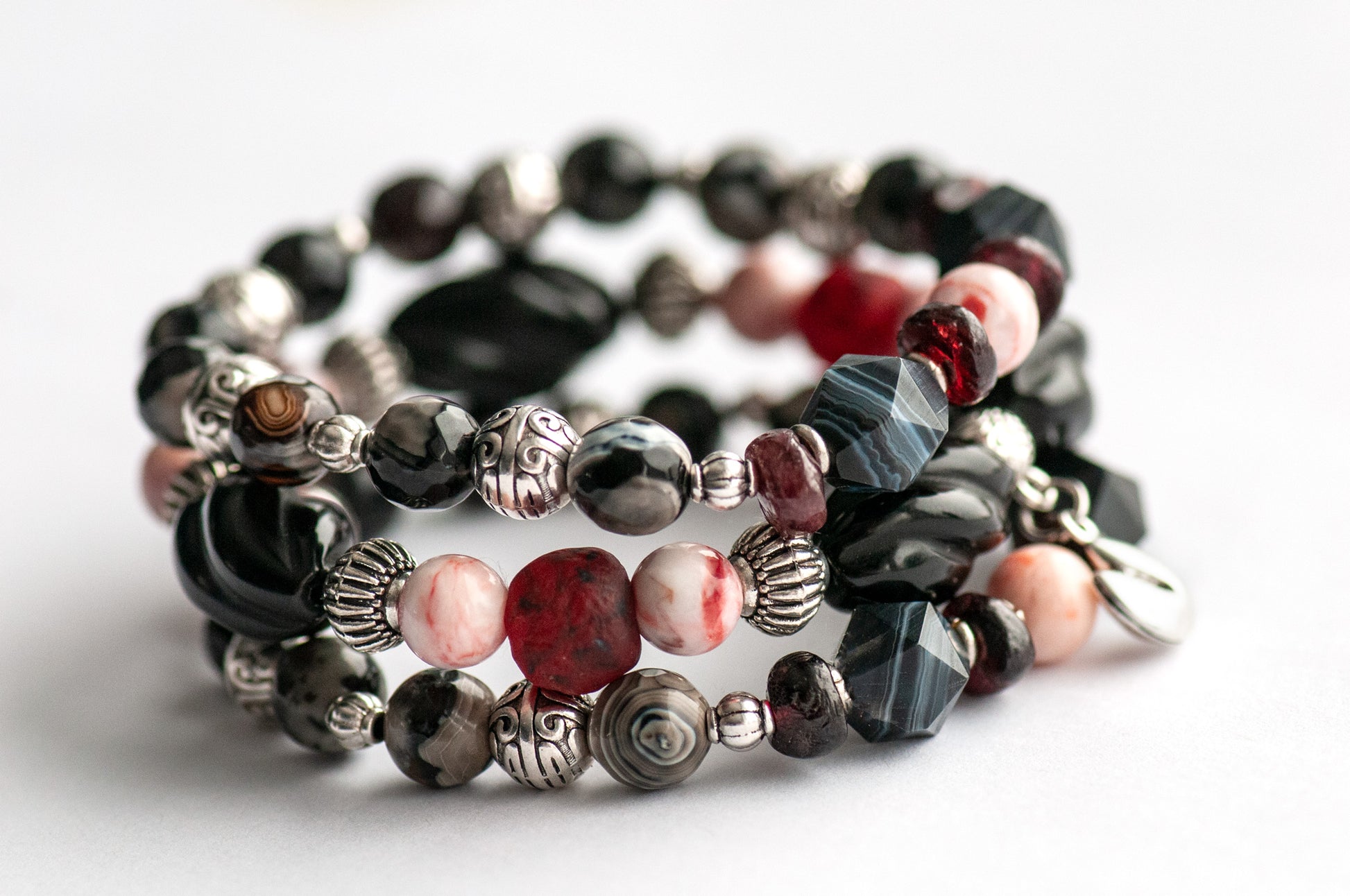 Voyage to Chinatown bracelet featuring a fortune cookie charm, spiral-carved Onyx beads, red and black swirl recycled glass, Cinnabarite beads, with Sardonyx and red garnet chips, complemented by silver-plated Chinese lantern spacers.