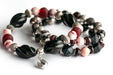 Voyage to Chinatown bracelet featuring a fortune cookie charm, spiral-carved Onyx beads, red and black swirl recycled glass, Cinnabarite beads, with Sardonyx and red garnet chips, complemented by silver-plated Chinese lantern spacers.