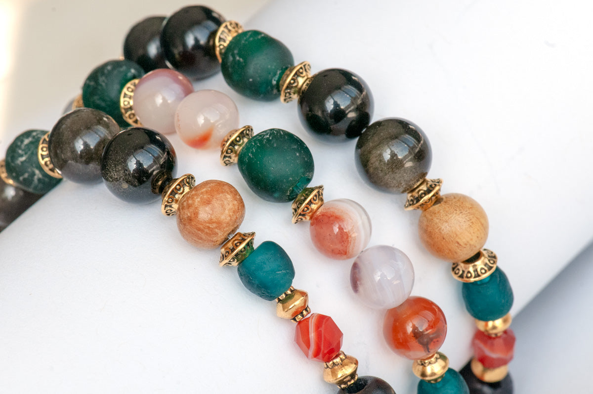 Handmade Voyage to Nairobi bracelet set featuring marquis-shaped Carnelian, red Sardonyx, dark teal recycled glass beads, and antique gold-plated spacers, inspired by African heritage.