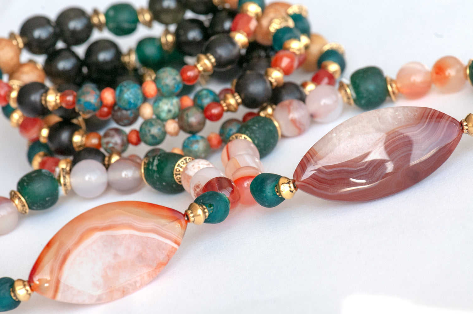 Handmade Voyage to Nairobi bracelet set featuring marquis-shaped Carnelian, red Sardonyx, dark teal recycled glass beads, and antique gold-plated spacers, inspired by African heritage.