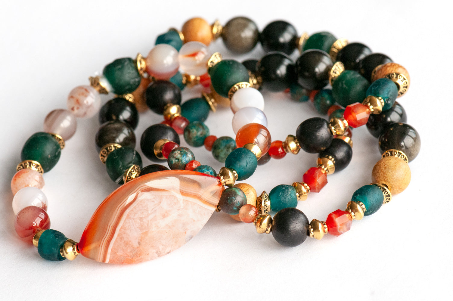 Handmade Voyage to Nairobi bracelet set featuring marquis-shaped Carnelian, red Sardonyx, dark teal recycled glass beads, and antique gold-plated spacers, inspired by African heritage.