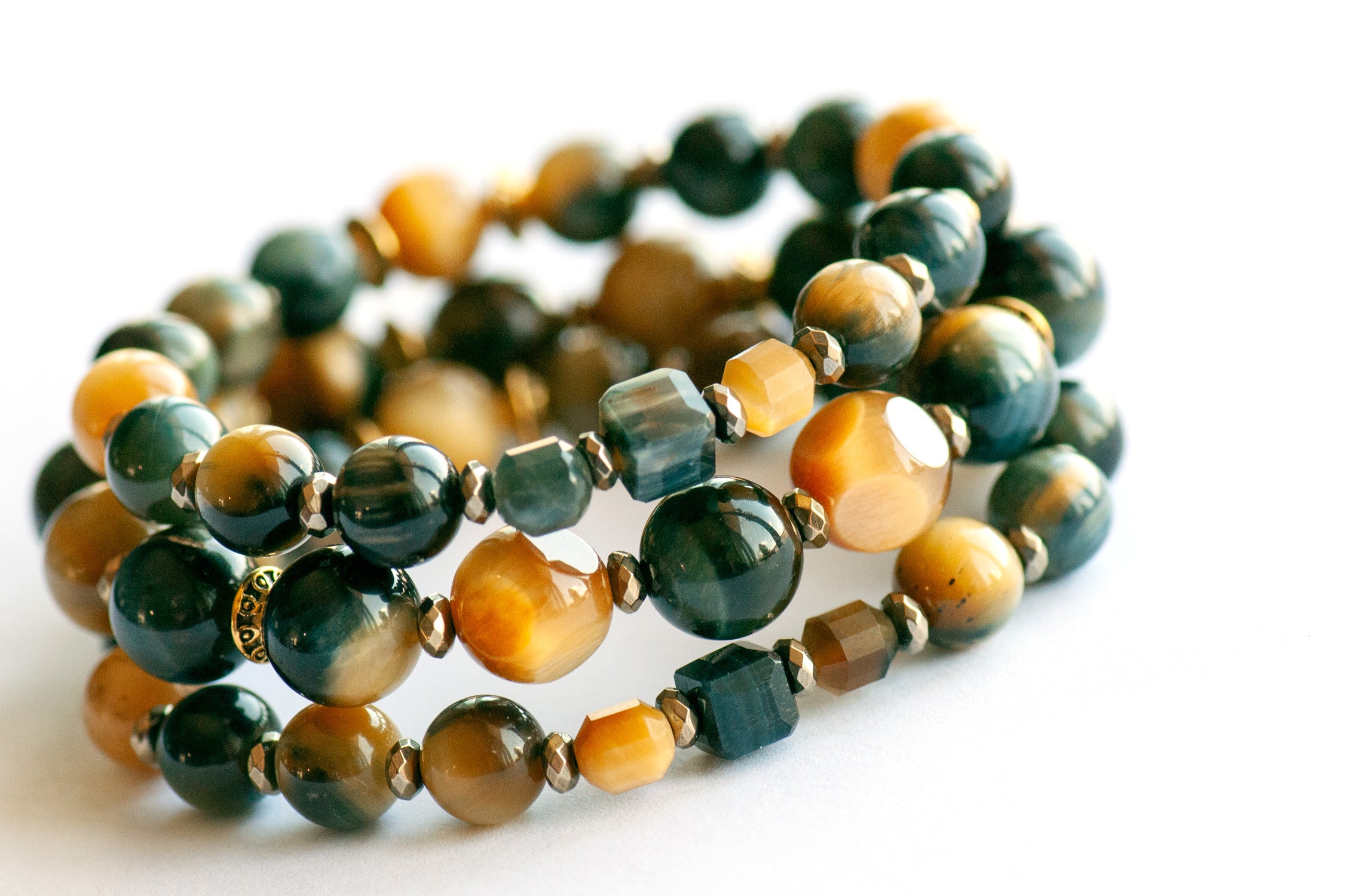 Tiger's Insight bracelet set featuring dark navy blue and golden yellow Tiger's Eye stones with chatoyant effects, accented by pyrite-plated hematite beads and antique gold spacers
