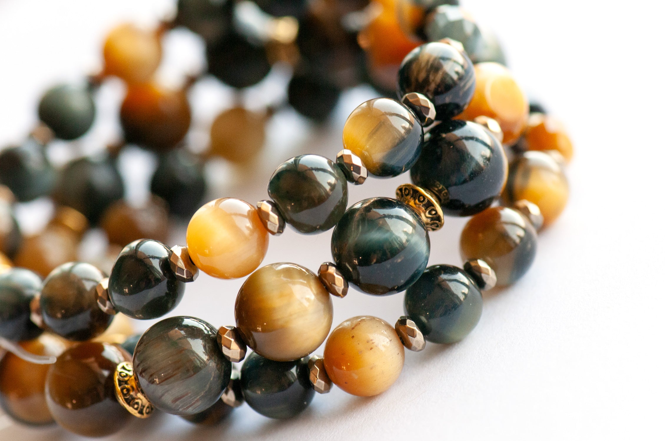 Tiger's Insight bracelet set featuring dark navy blue and golden yellow Tiger's Eye stones with chatoyant effects, accented by pyrite-plated hematite beads and antique gold spacers