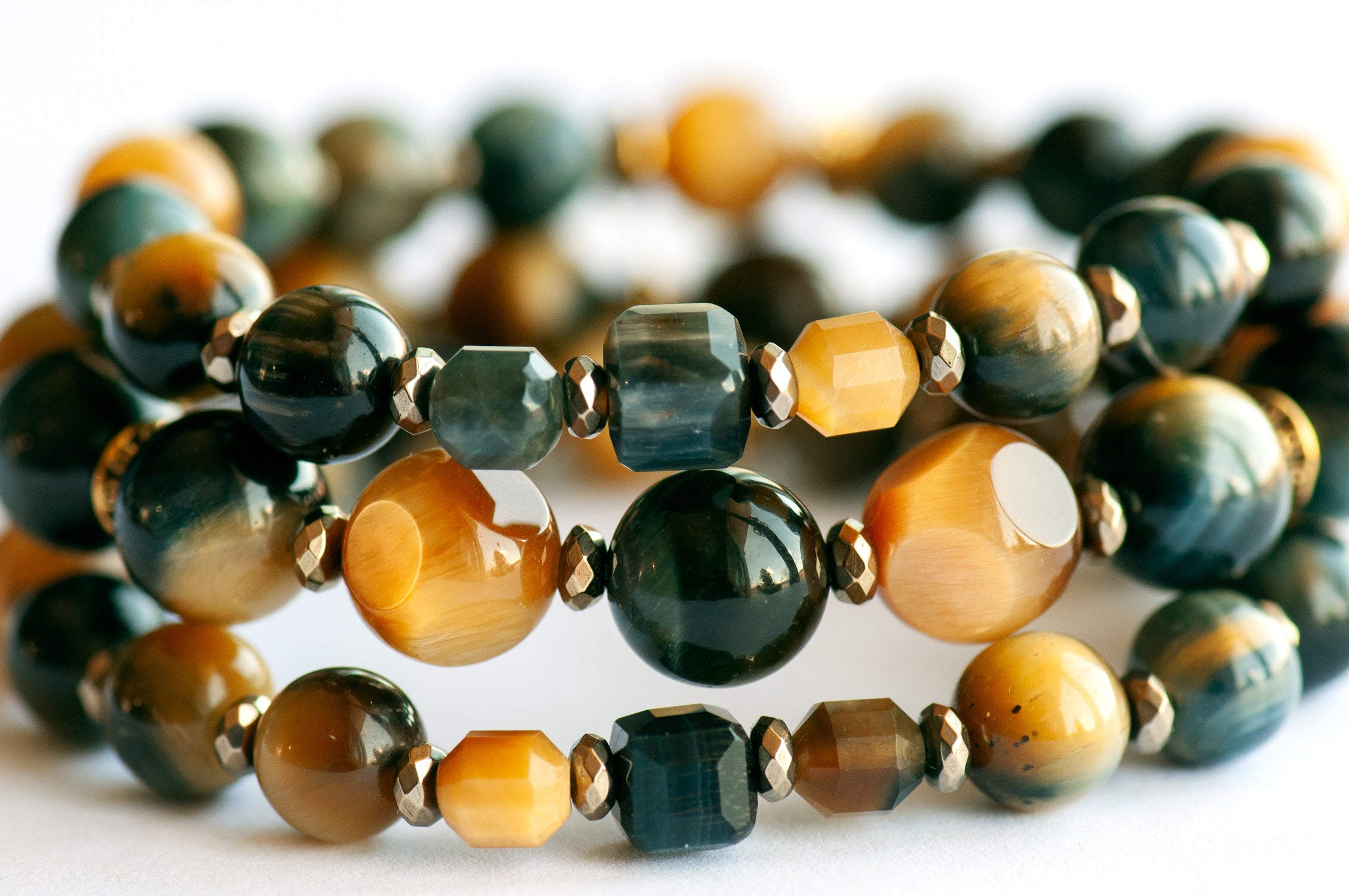 Tiger's Insight bracelet set featuring dark navy blue and golden yellow Tiger's Eye stones with chatoyant effects, accented by pyrite-plated hematite beads and antique gold spacers