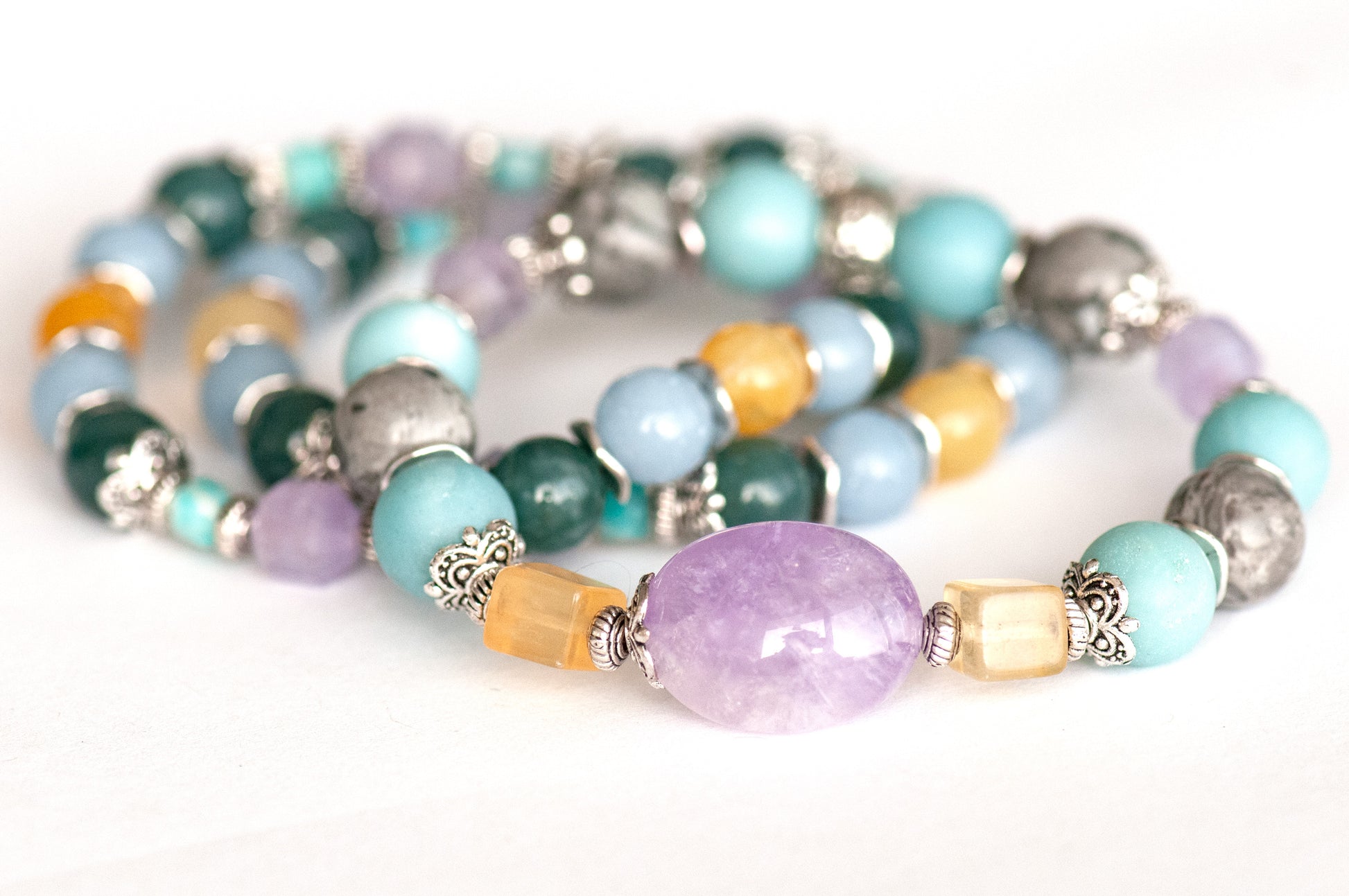 Close-up of the focal bracelet with a 15mm lavender amethyst nugget framed by bright yellow fluorite cubes, matte amazonite, and silver crazy lace agate rounds.
