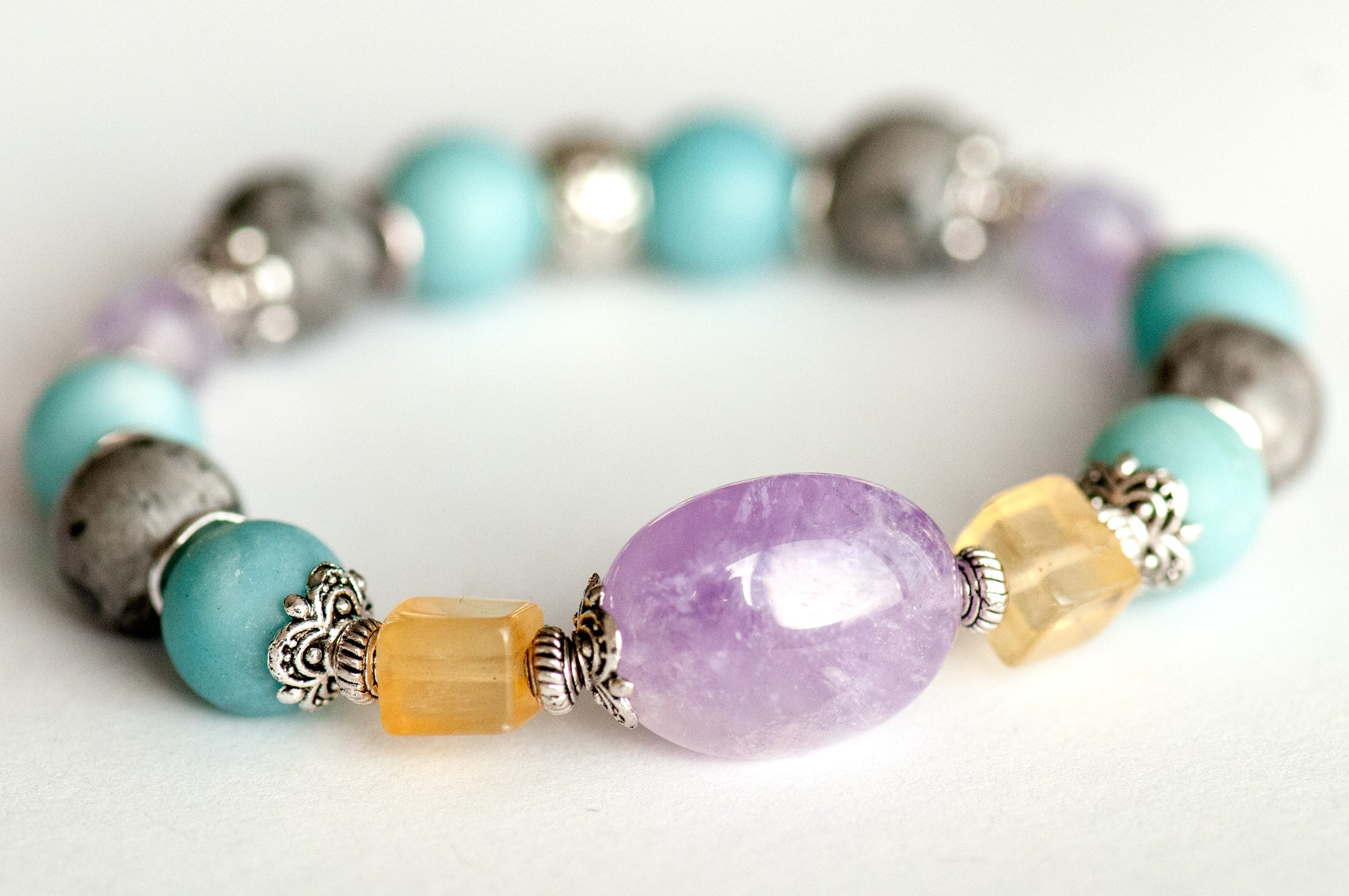 Close-up of the focal bracelet with a 15mm lavender amethyst nugget framed by bright yellow fluorite cubes, matte amazonite, and silver crazy lace agate rounds.