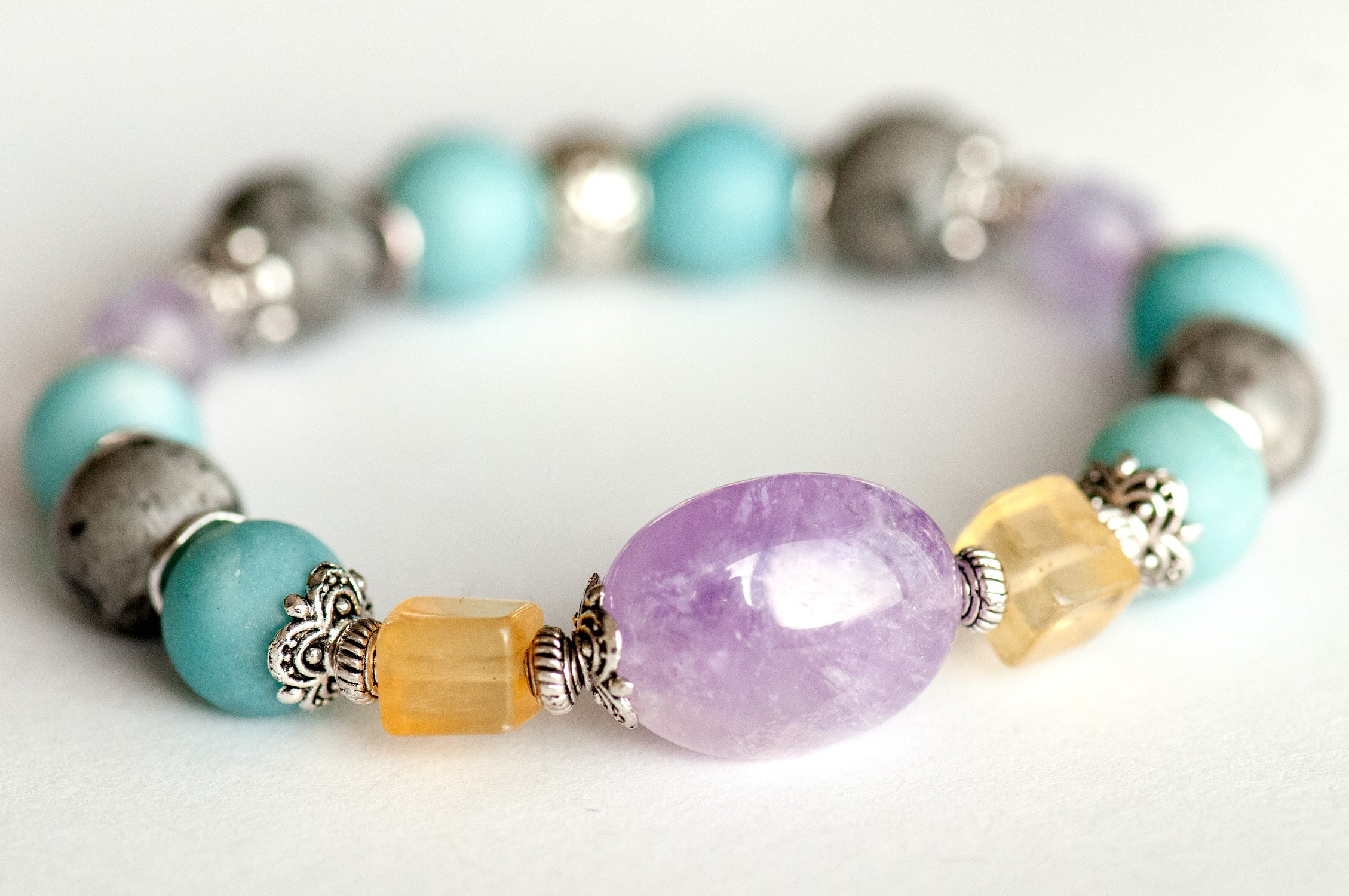 Close-up of the focal bracelet with a 15mm lavender amethyst nugget framed by bright yellow fluorite cubes, matte amazonite, and silver crazy lace agate rounds.