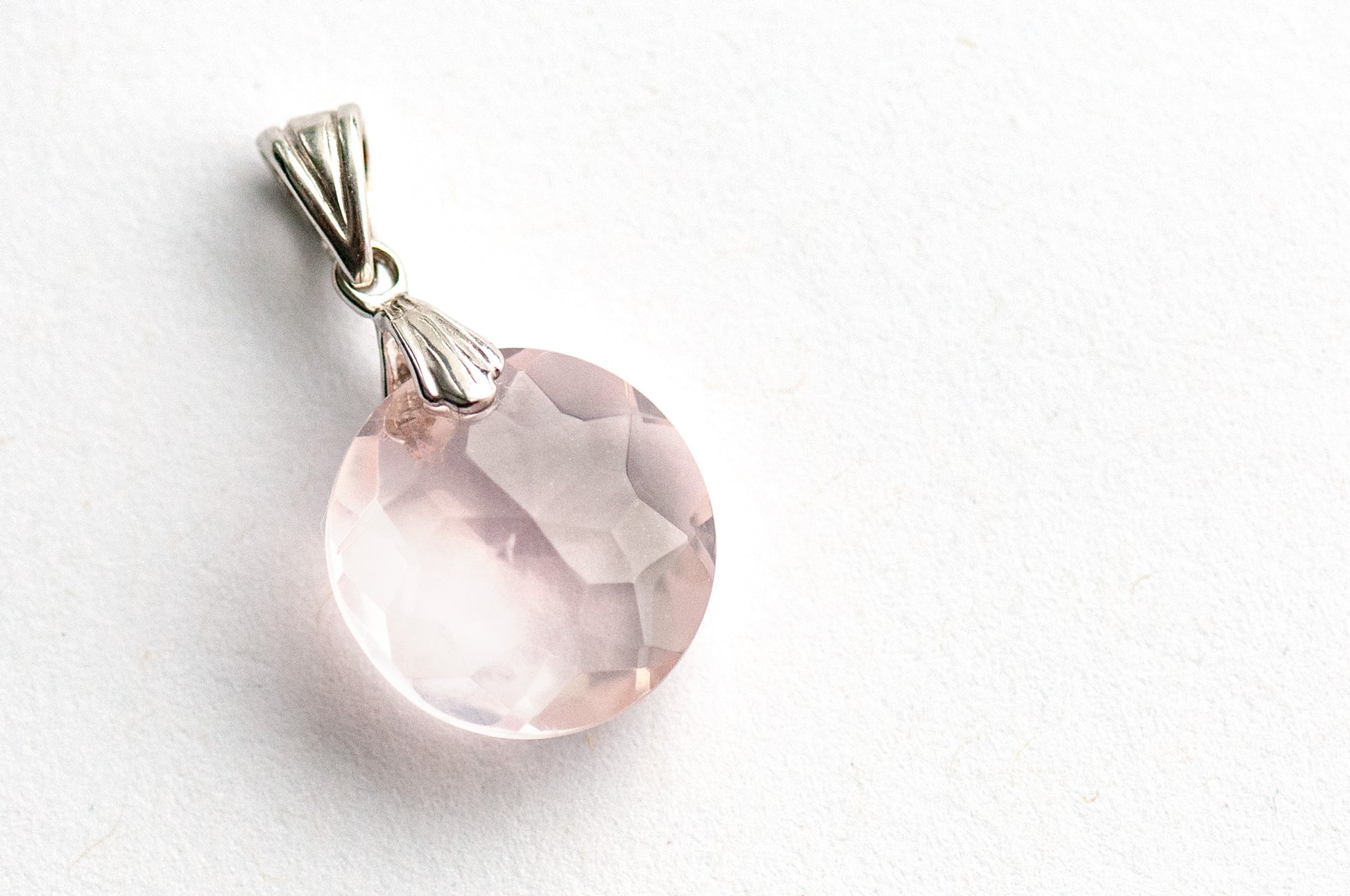 Rose Quartz Glow Lynx pendant featuring a 14mm Rose Quartz coin with a starburst facet pattern and sterling silver bail.
