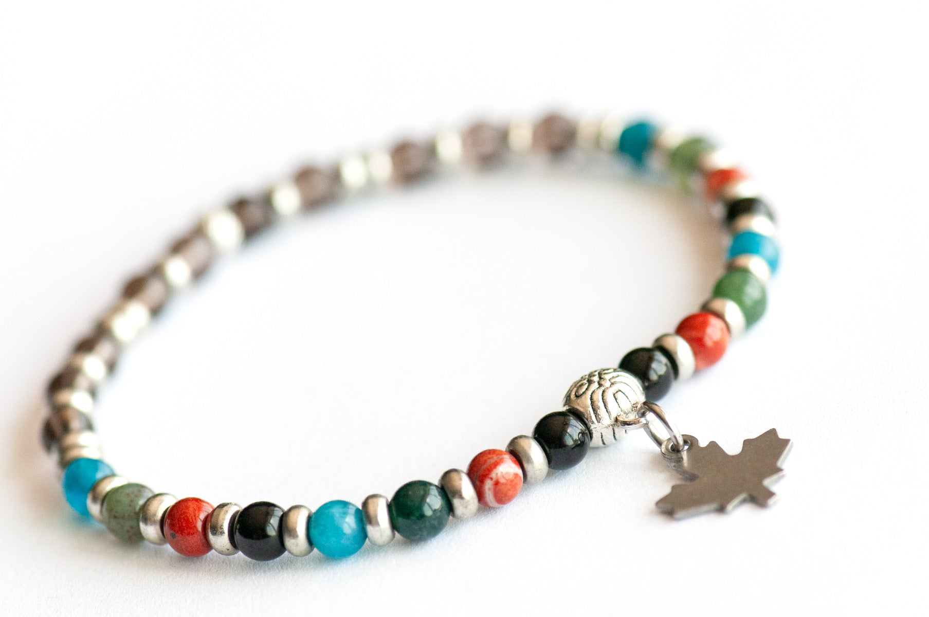 Supporting bracelet from New Brunswick Lynx Set – 4mm round stones with charm, including Black Tourmaline, Red Jasper, Moss Agate, Blue Apatite, and Smoky Quartz