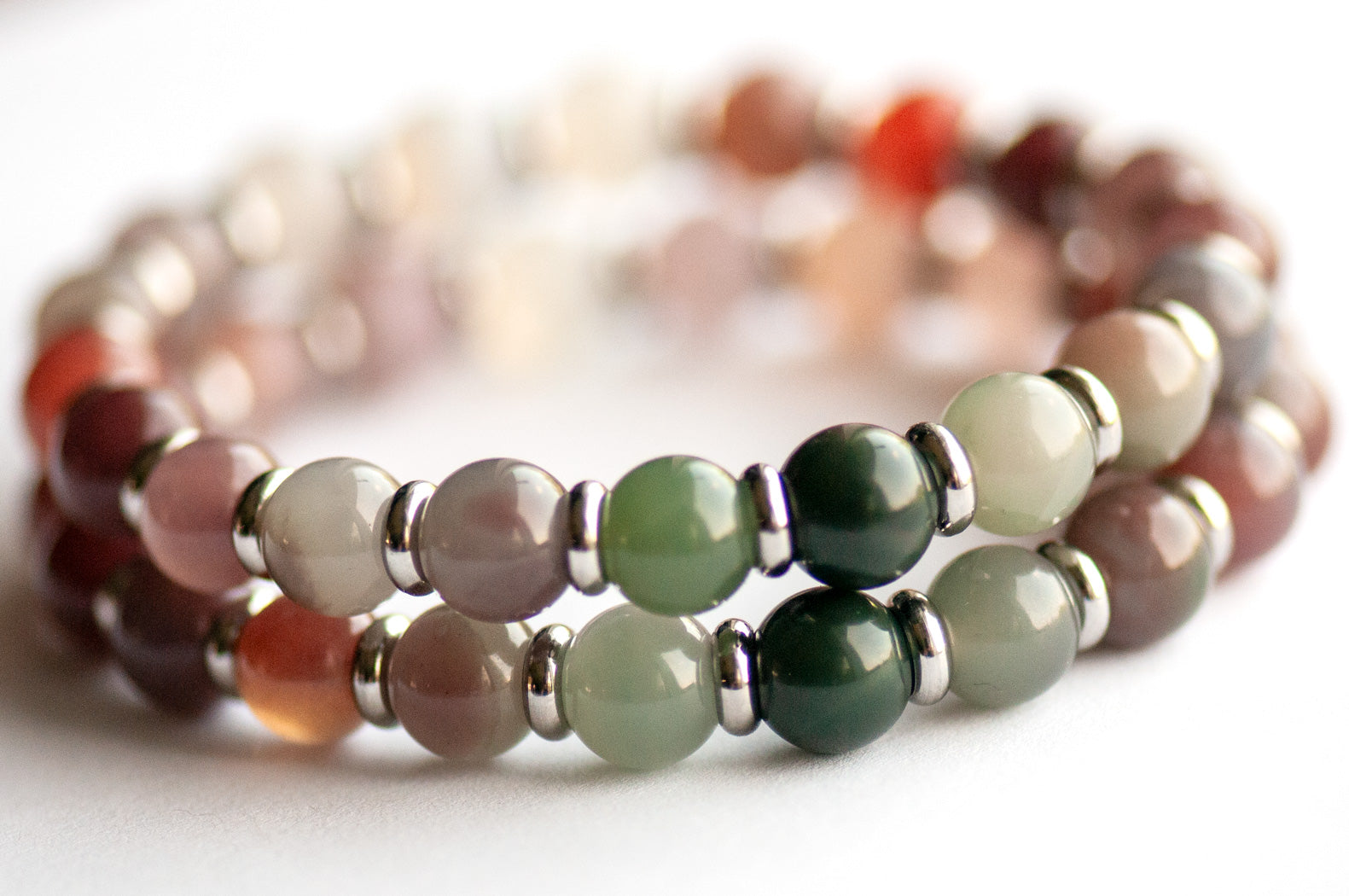 Close-up of Phantom Agate gradient beads in pink, mauve, and forest green tones