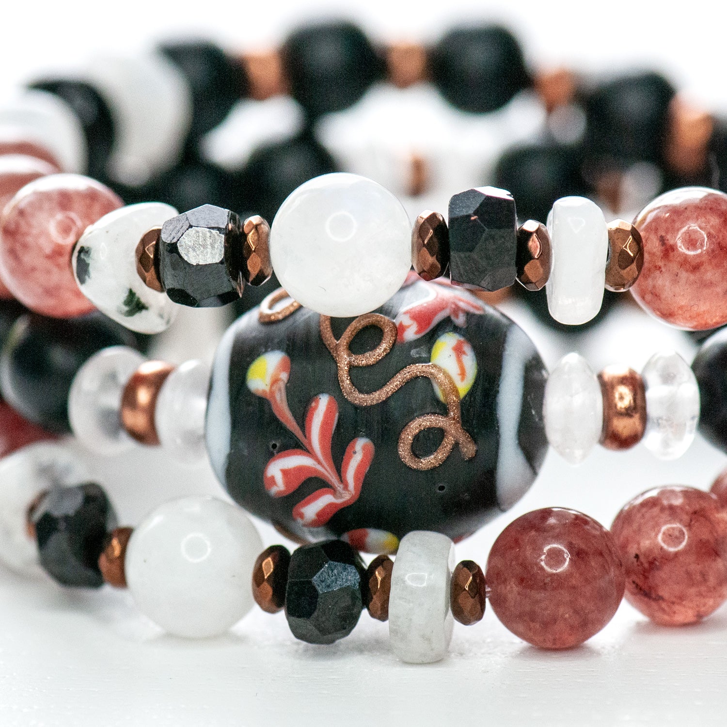 Venetian-style glass bead with sakura-inspired fuchsia and copper blooms on matte black background