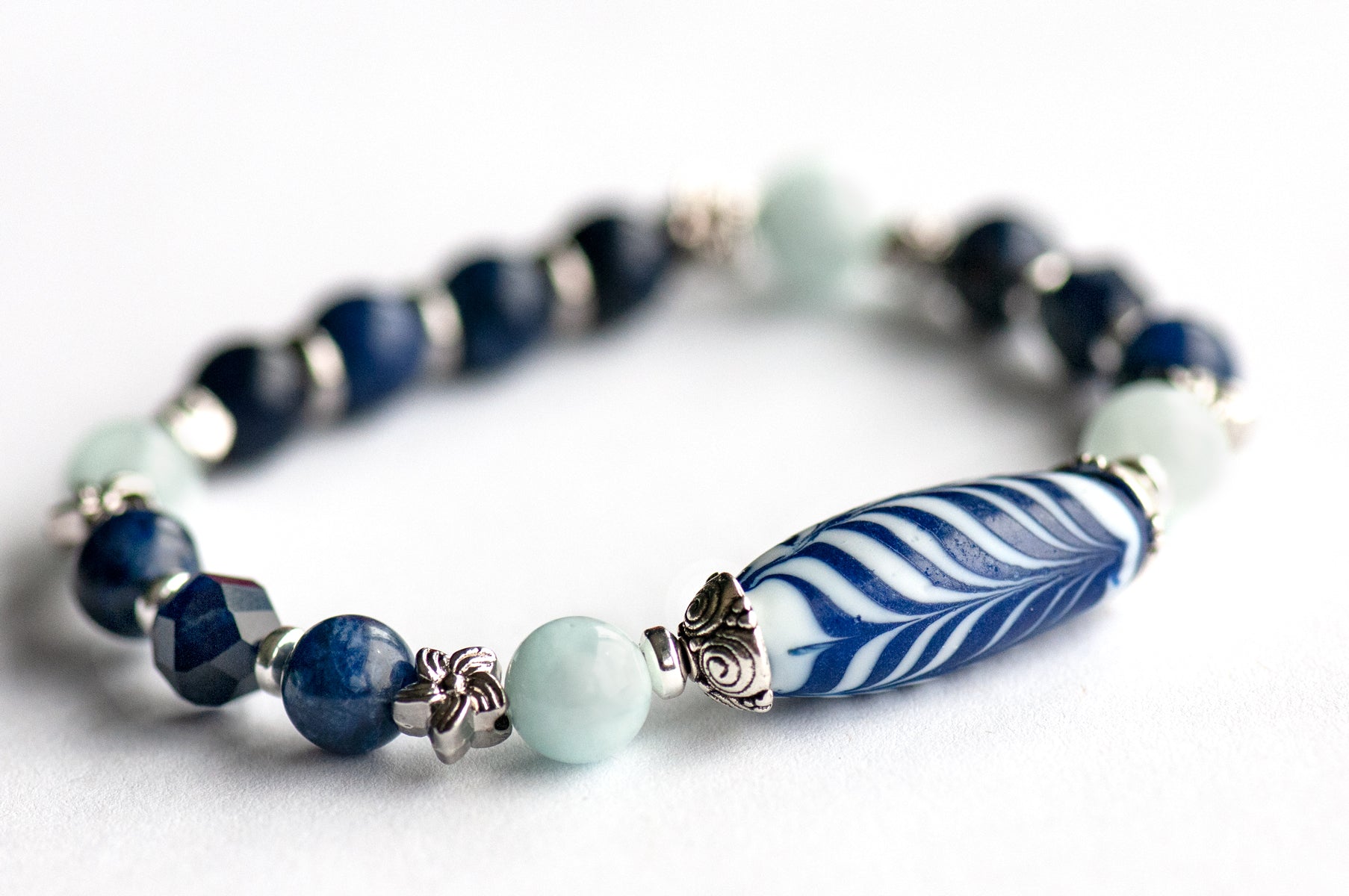 Larkspur Bracelet Set: Aquamarine, Sodalite & a handmade glass feather bead celebrate July's birth flower — open-hearted, light, and full of summer grace.