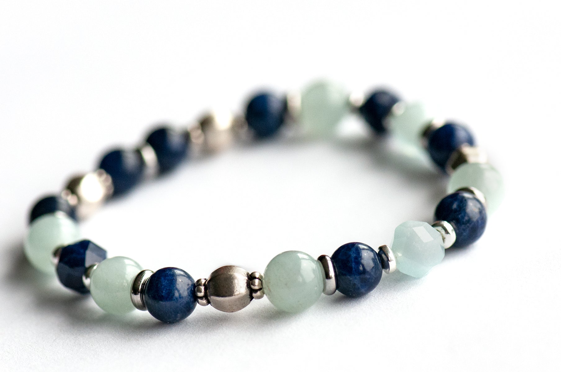 Larkspur supporting bracelet: Aquamarine, Sodalite & a handmade glass feather bead celebrate July's birth flower — open-hearted, light, and full of summer grace.