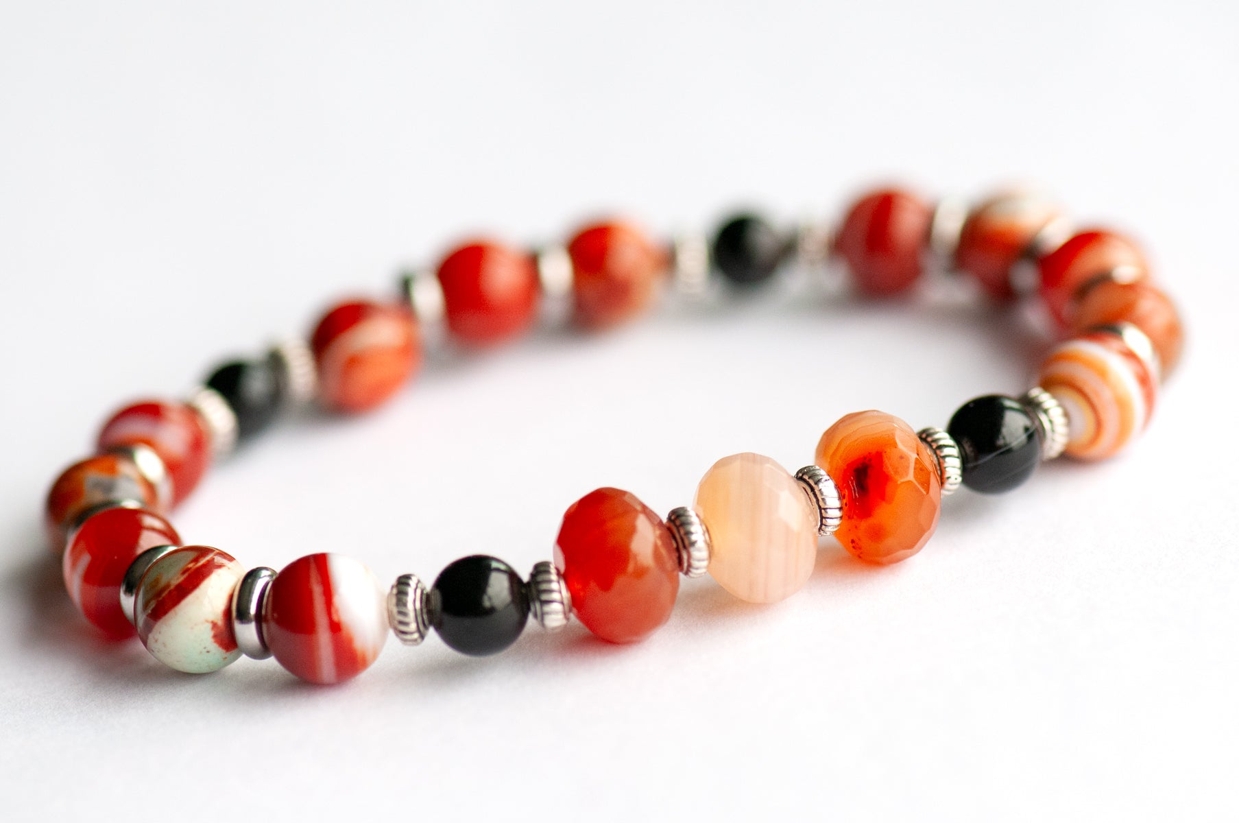 Poppy supporting bracelet: Black Onyx, Red Agate & Flower Poppy Jasper celebrate August's birth flower — bold resilience in deep burnt reds and grounding black.