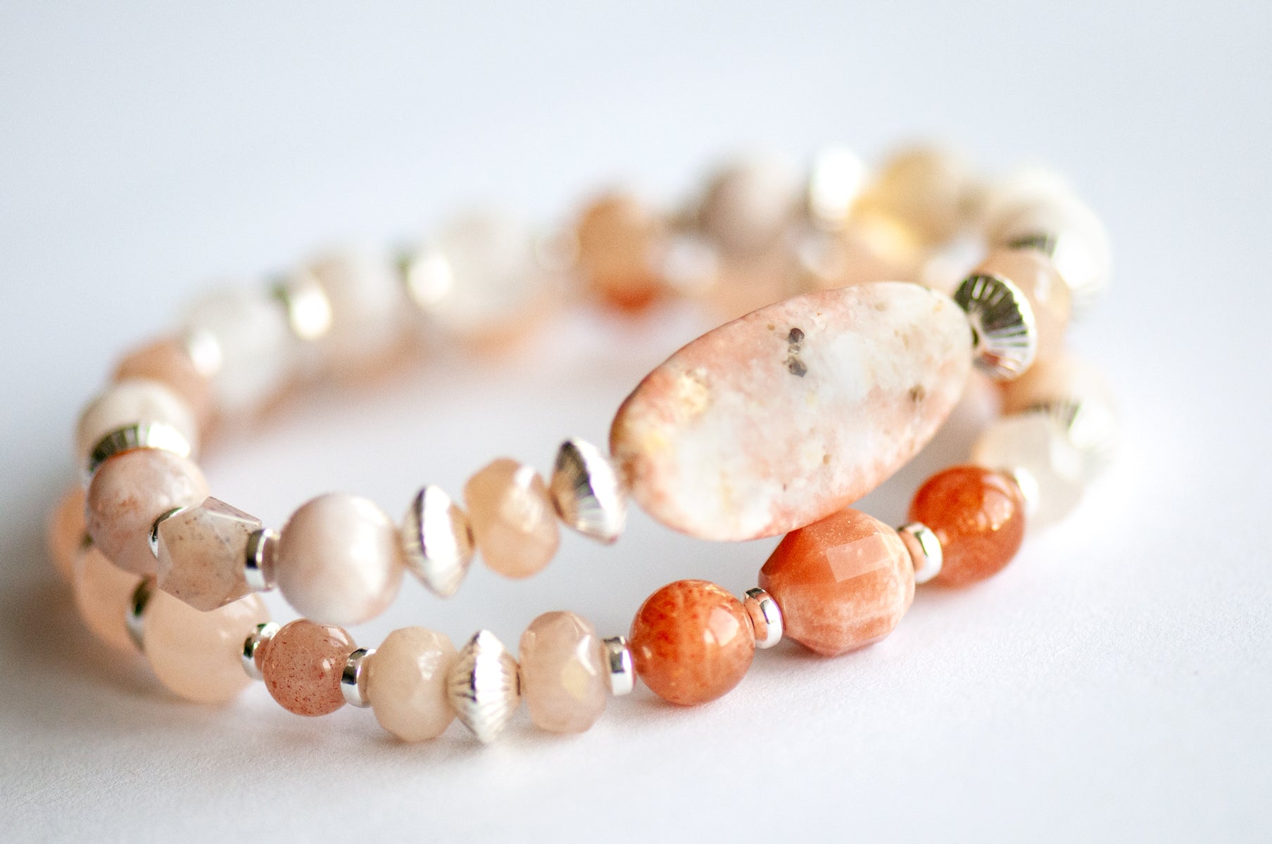 Chrysanthemum November birth flower bracelet set — side view, two bracelets showing peachy gold and blush gemstone rounds with silver hematite spacers