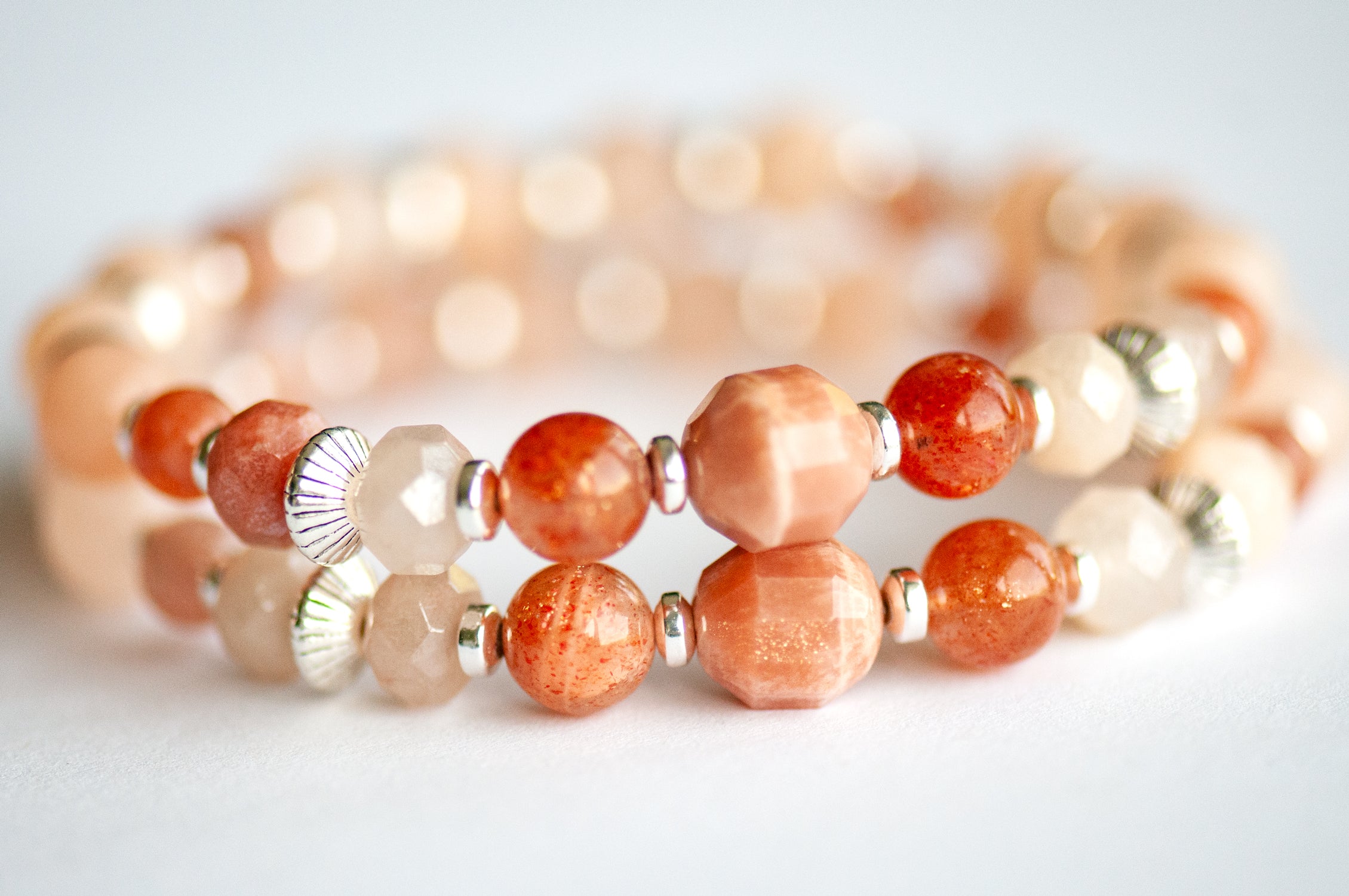 close up of the two supporting bracelets with peach moonstone and sunstone beads