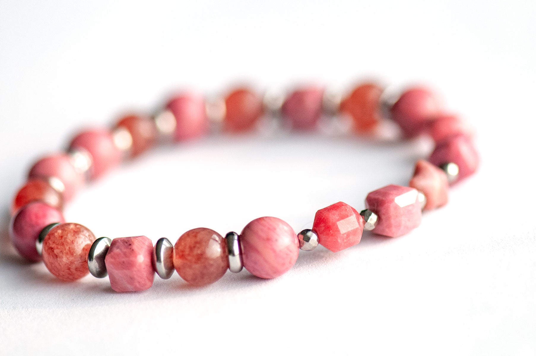Carnation January birth flower supporting bracelet — side view, showing Grade A Rhodonite, Sakura Lodolite Quartz and stainless steel spacers in soft blush and berry tones