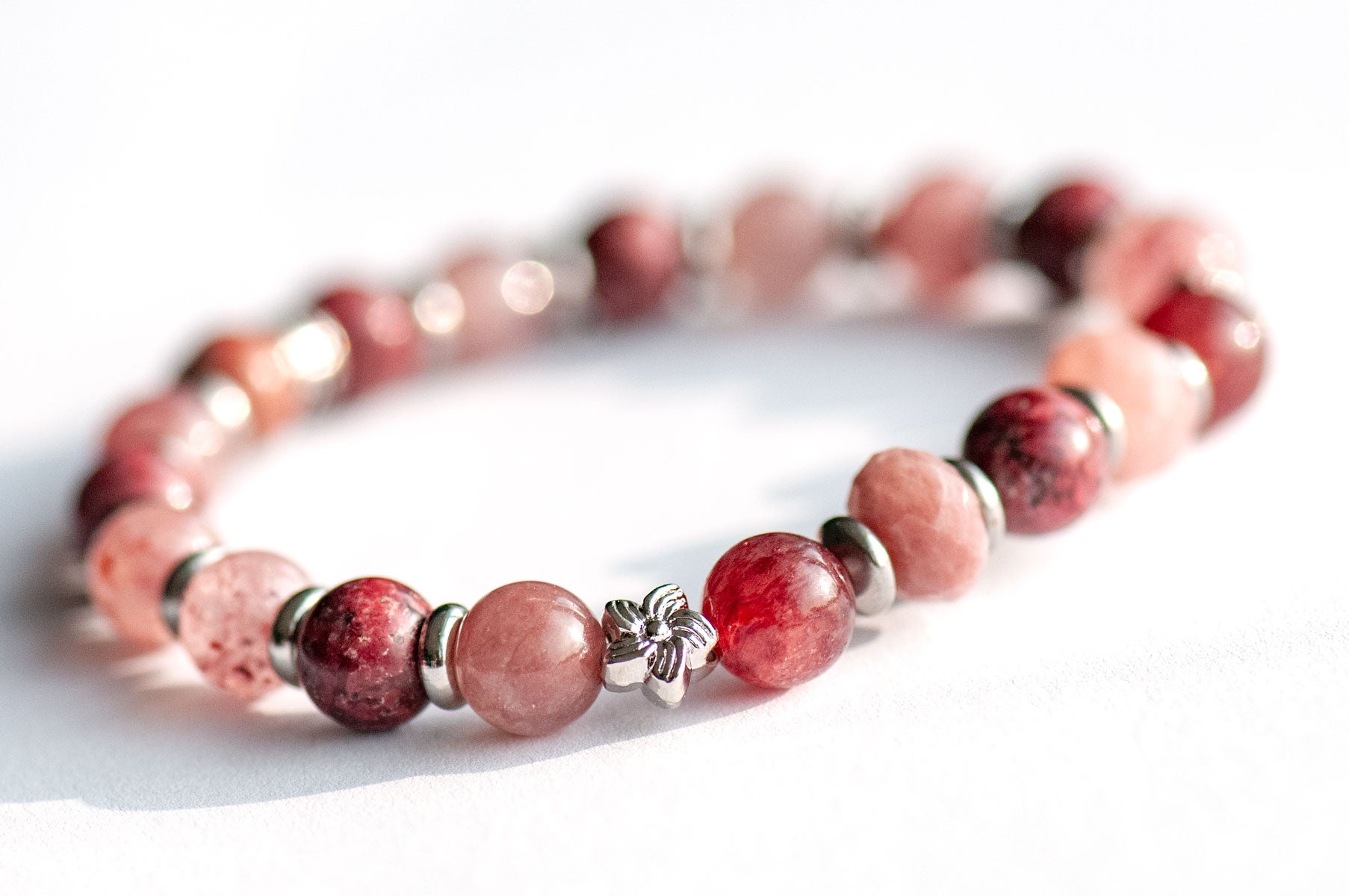Carnation January birth flower focal bracelet — side view, showing depth and sparkle of Eudialyte and Strawberry Quartz rounds with platinum flower spacers