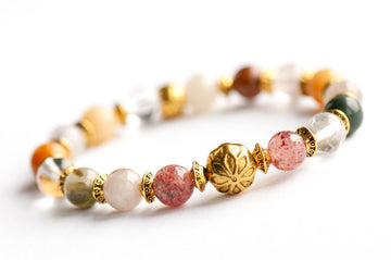 Introducing the Fierce Multitude - Lodalite Quartz Bracelet by Fierce Lynx Designs, a vintage-inspired gold-plated bracelet adorned with multicolored lodalite quartz gemstones and elegant gold accents—highlighted by a central gold bead embossed with an intricate floral motif—beautifully showcased against a crisp white background.