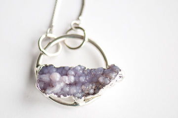 Close-up of a raw Purple Grape Agate cluster set along the base of a silver hoop pendant.