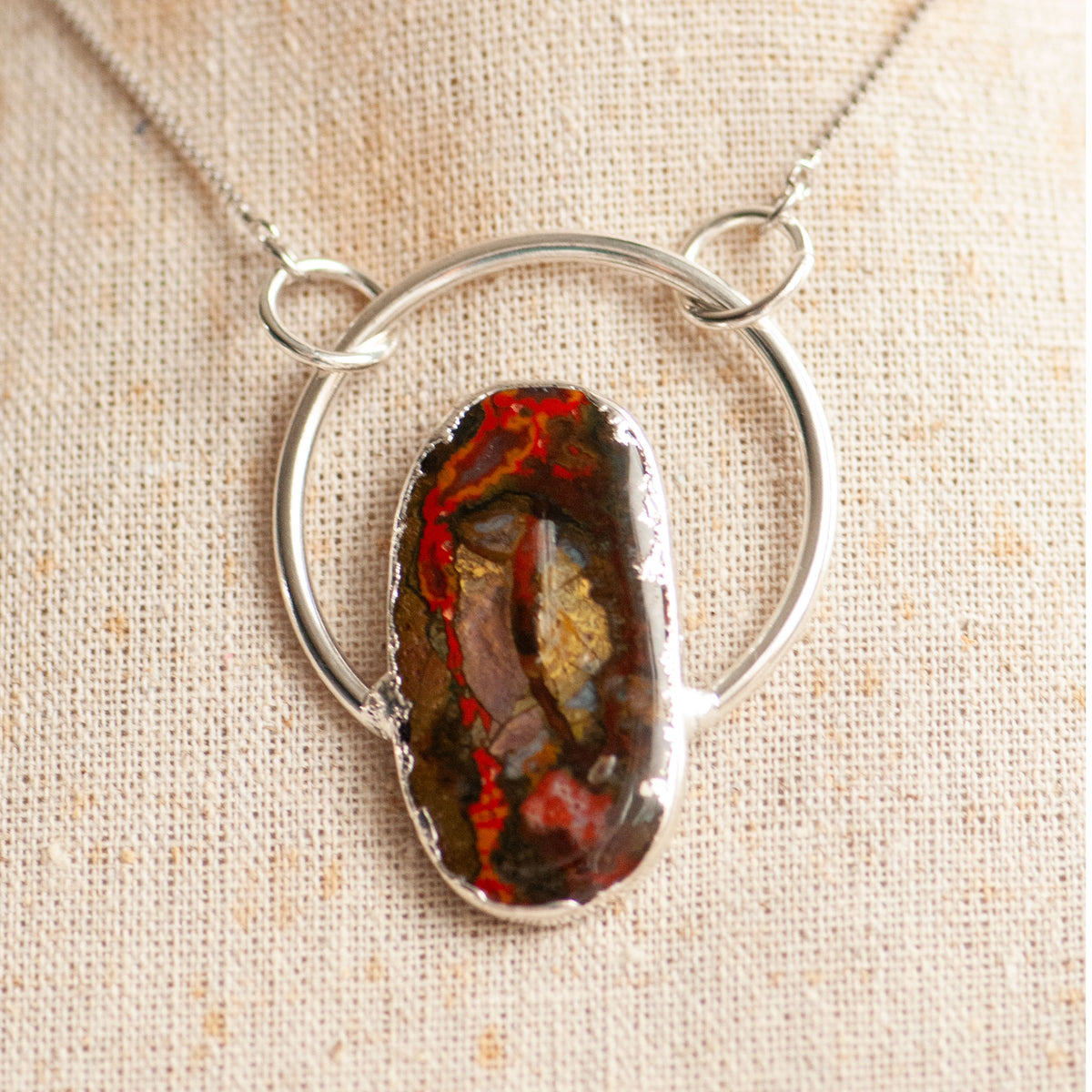 Close-up of a Moroccan Seam Agate pendant in an electroformed silver hoop, shown on a linen bust.