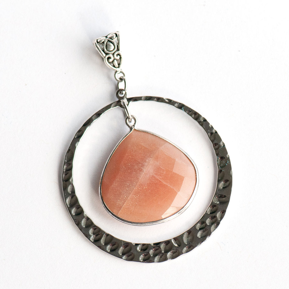 Sunlit Lynx peach moonstone teardrop pendant hanging inside a textured silver ring.