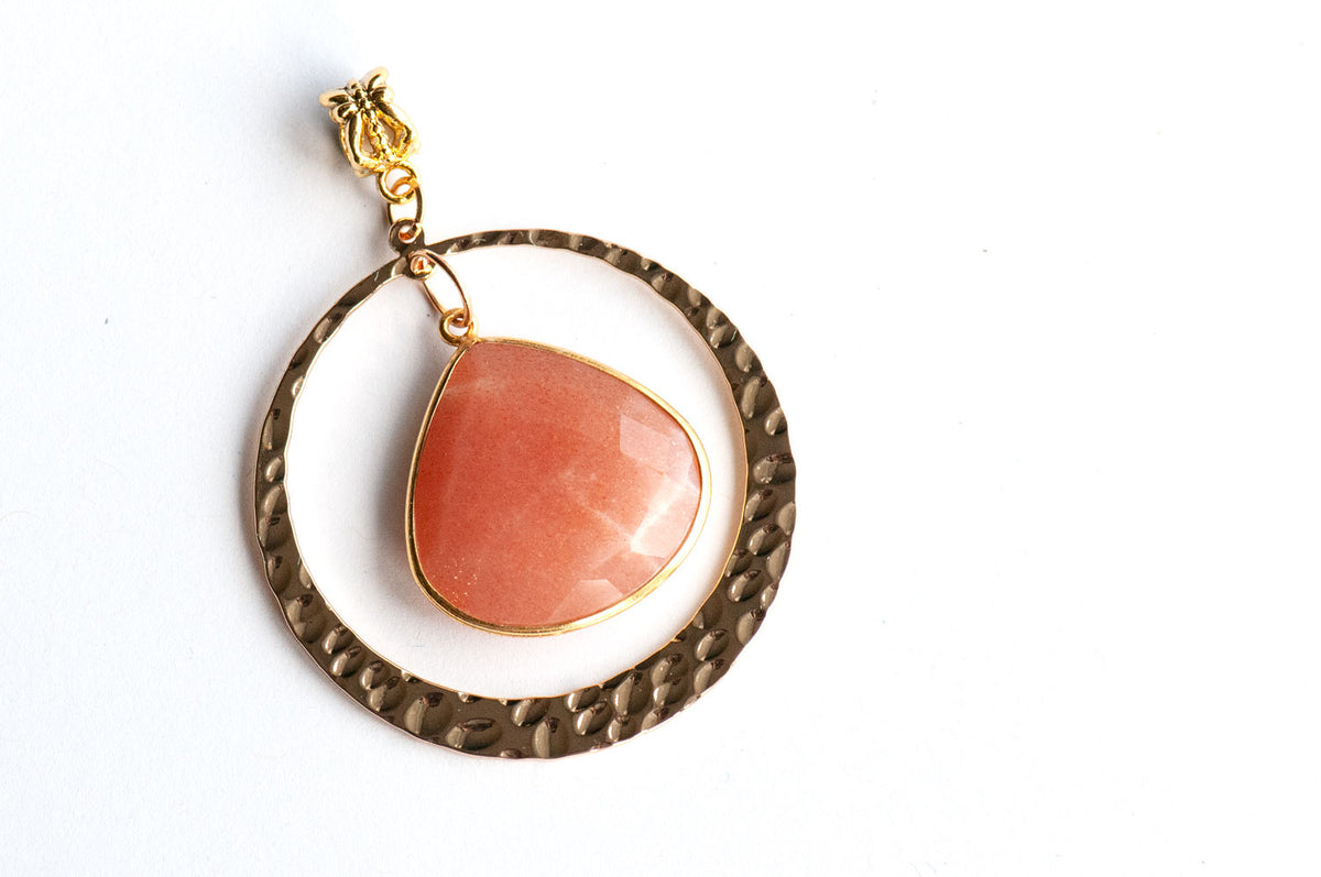 Gold Sunlit Lynx pendant with a faceted Peach Moonstone in a gold bezel, hammered gold ring, and ornate bail.