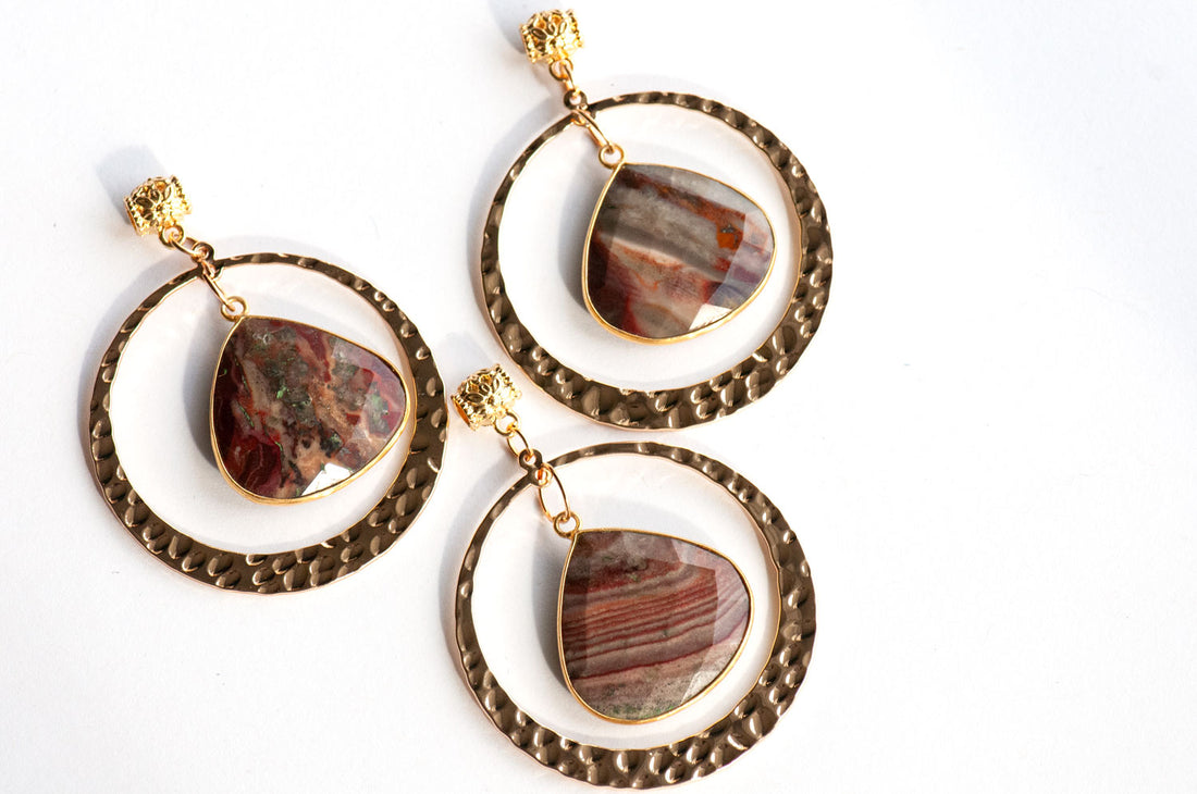 Three Fireside Lynx earrings, each featuring a dangling, teardrop-shaped polychrome jasper pendant in a gold-toned hoop.