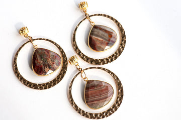 Three Fireside Lynx earrings, each featuring a dangling, teardrop-shaped polychrome jasper pendant in a gold-toned hoop.