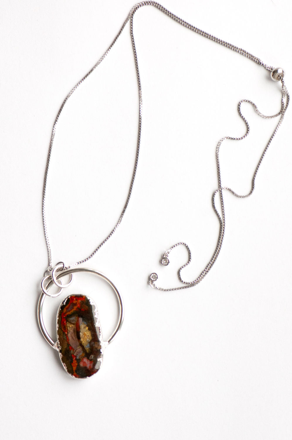 Moroccan Seam Agate hoop pendant on a silver box chain, laid flat with the slider bead and crystal-tipped chain ends showing.