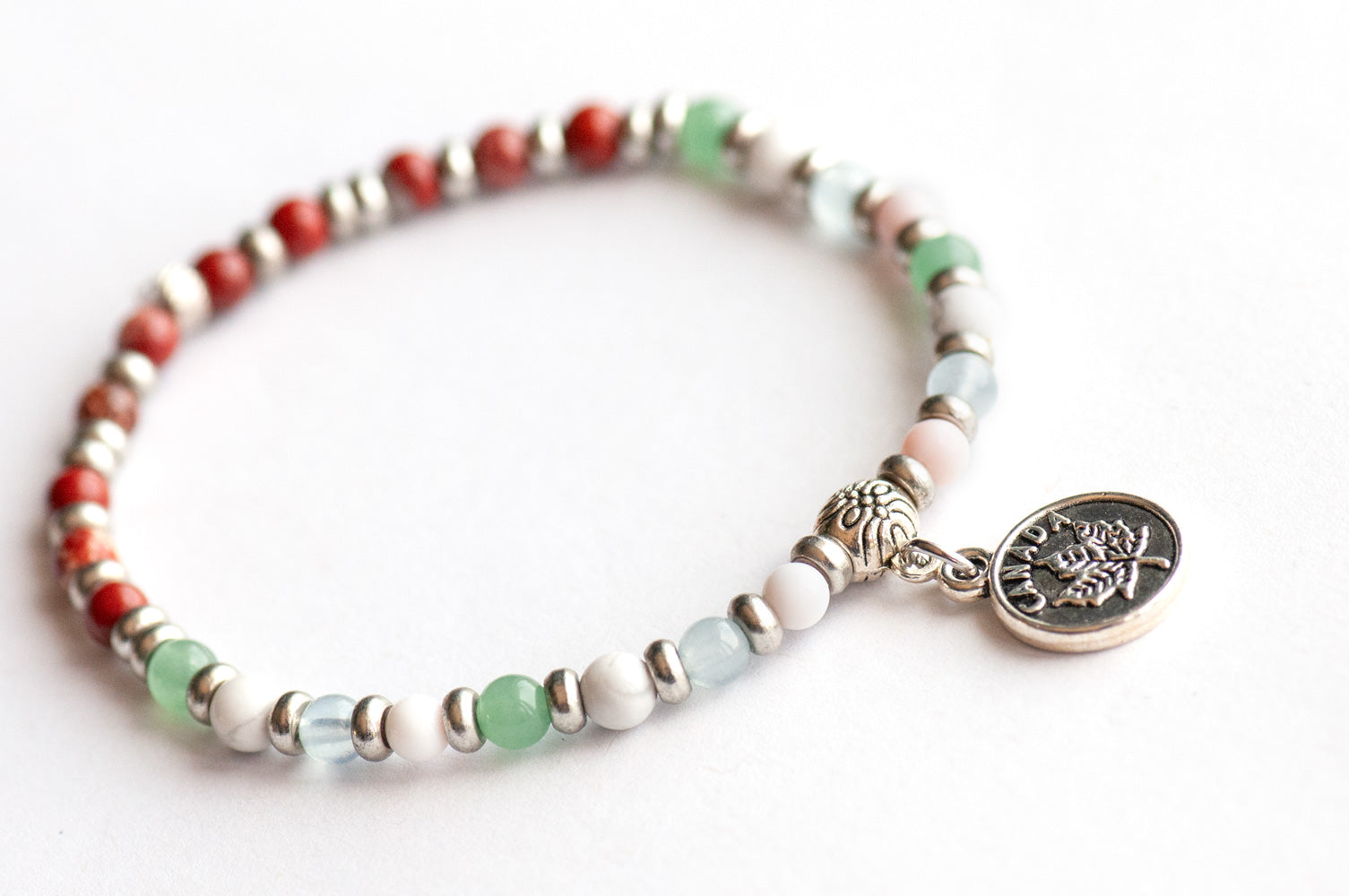 Supporting bracelet from Prince Edward Island Lynx Set – 4mm stones with charm, including Red Jasper, Green Aventurine, White Howlite, Aquamarine, and Queen Conch Shell